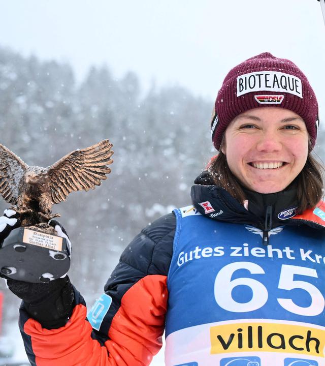 Agnes Reisch hält die Trophäe für ihren dritten Platz beim Skispringen in Villach in der rechten Hand.