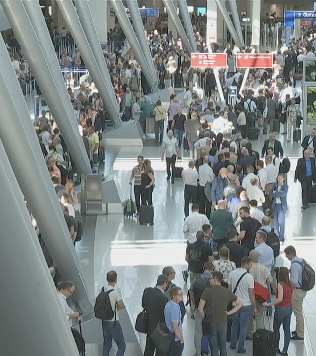 Viele Reisende am Flughafen Düsseldorf in Warteschlangen.