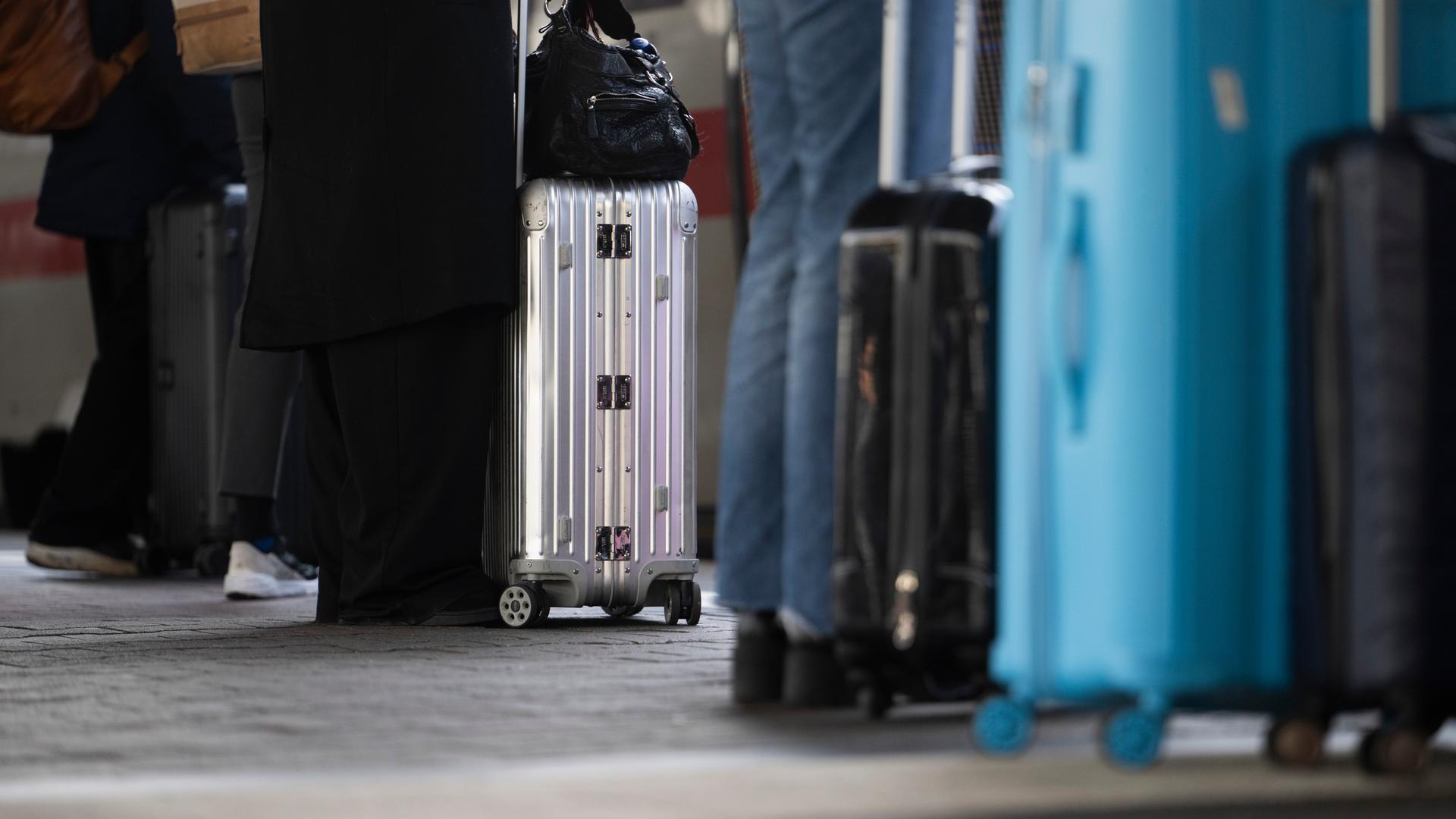 Reisende stehen mit ihrem Gepäck an einem Gleis am Hauptbahnhof.