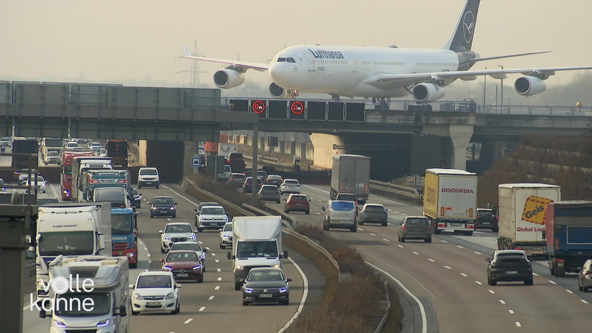Flugzeug landet auf Landebahn, die über einer gut befahrenen Autobahn gelegen ist