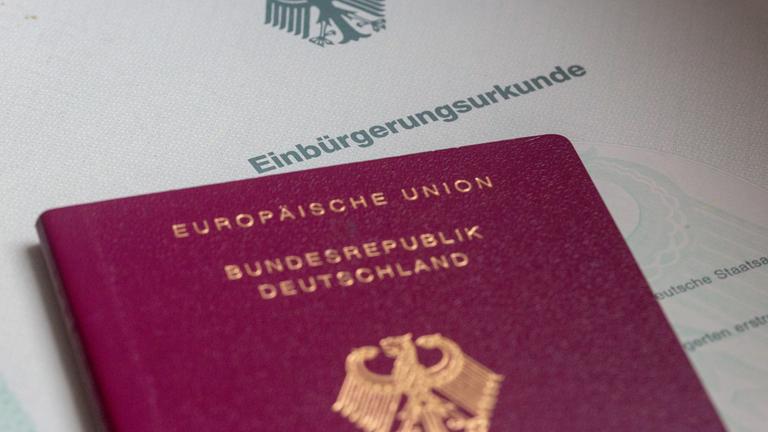 Einbürgerungsurkunde im Hintergrund mit deutschem Pass im Vordergrund