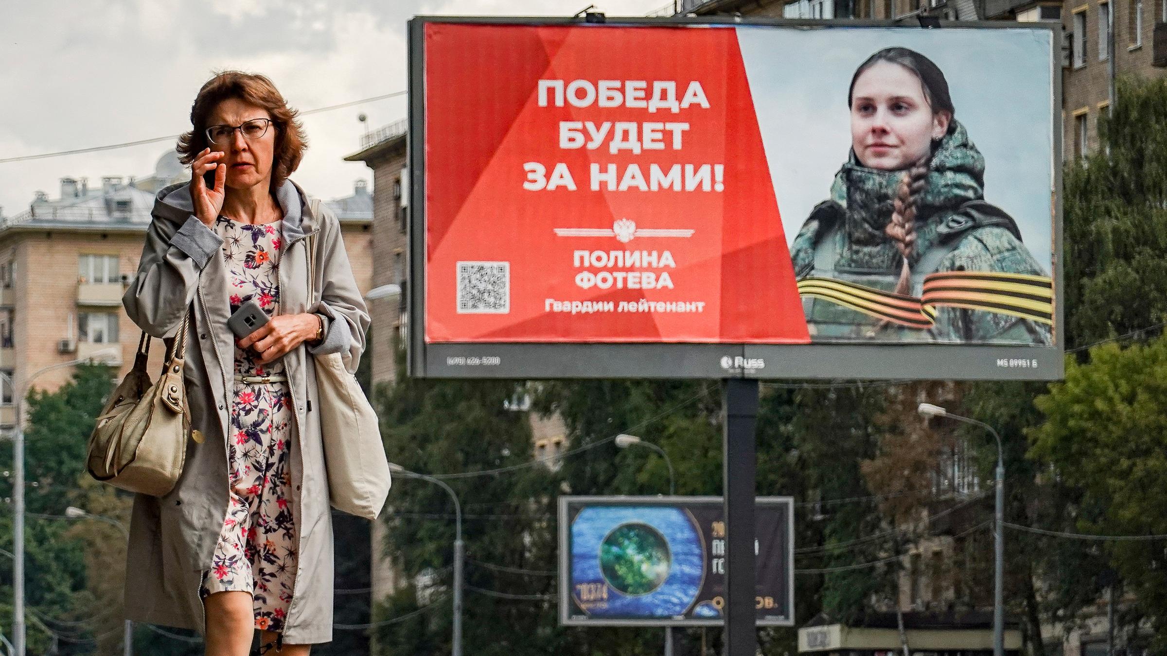 Eine russische Frau geht vor einem Plakat mit der Aufschrift "Der Sieg wird unser sein" in Moskau, aufgenommen am 25.08.2023
