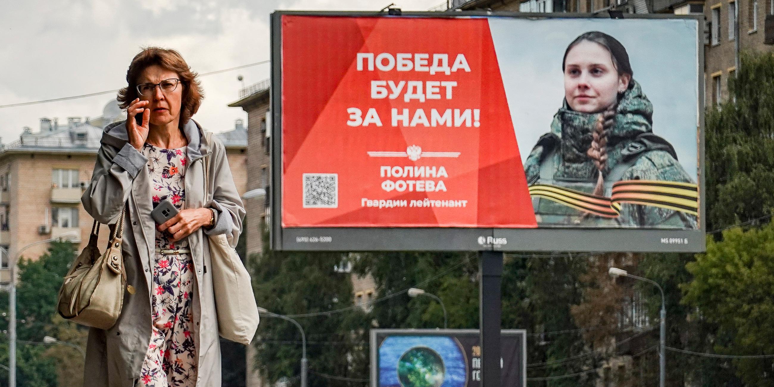 Eine russische Frau geht vor einem Plakat mit der Aufschrift "Der Sieg wird unser sein" in Moskau, aufgenommen am 25.08.2023
