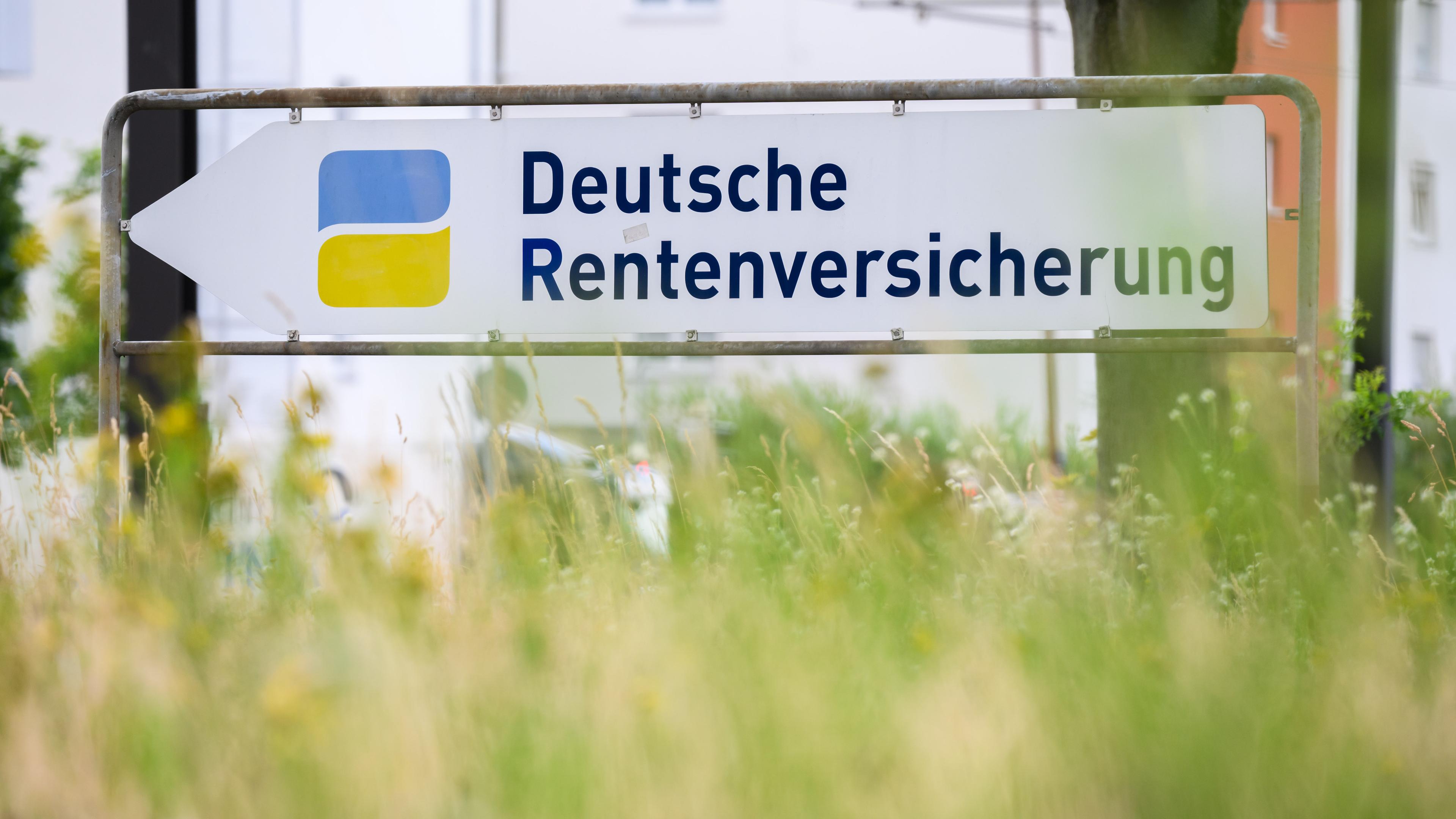 Ein Schild in einer Wiese weist den Weg zur der Deutschen Rentenversicherung.