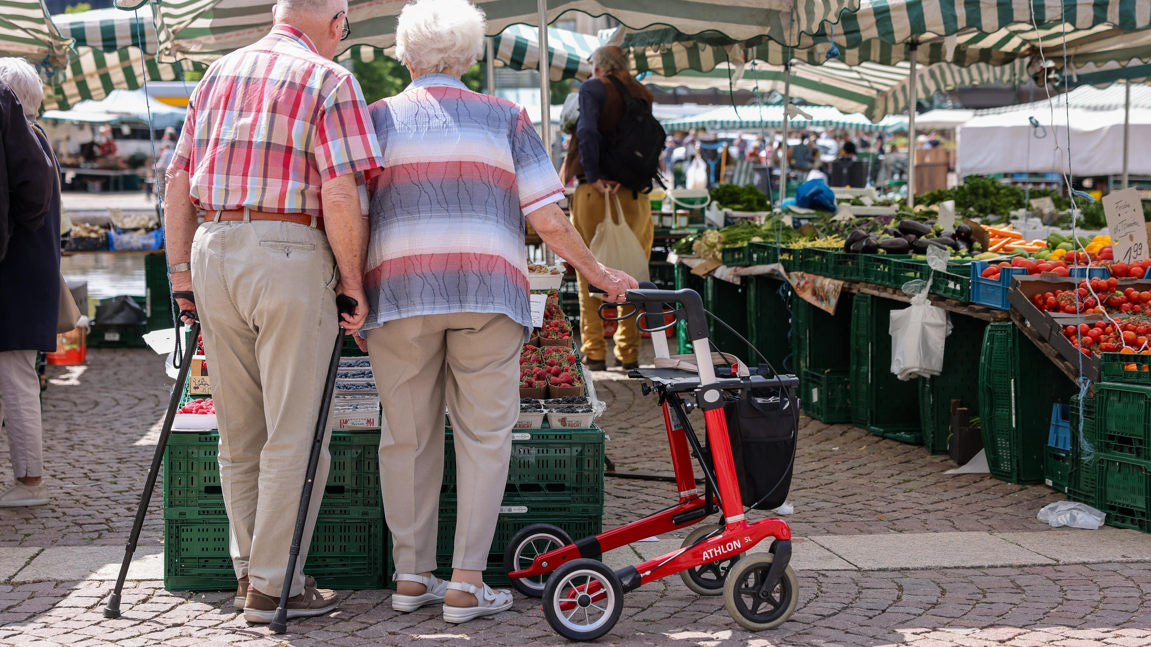 Sachsen, Leipzig: Zwei Senioren stehen mit Gehhilfen und Rollator auf dem Wochenmarkt