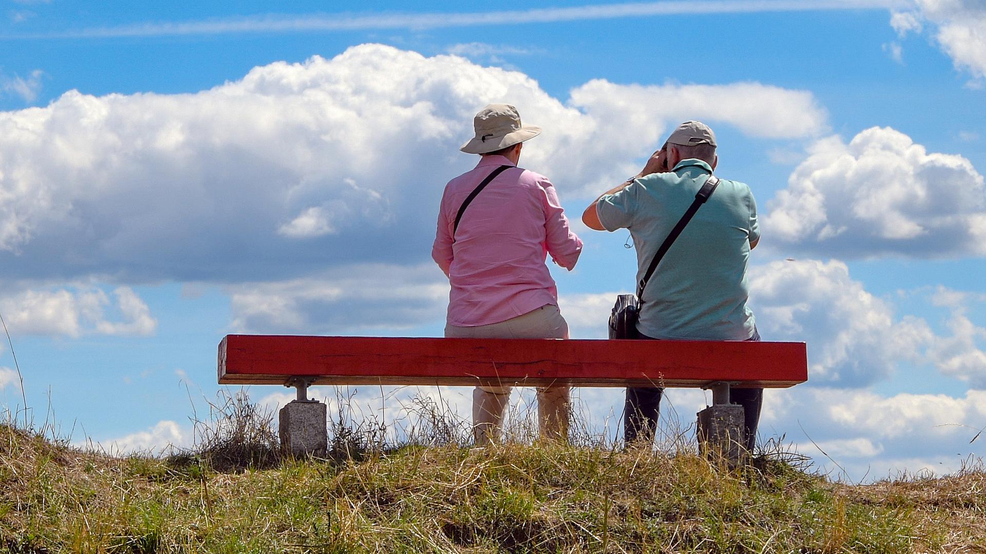 Zwei ältere Personen sitzen auf einer Bank, die auf einem Hügel im Nationalpark Unteres Odertal steht, aufgenommen am 23.07.2020
