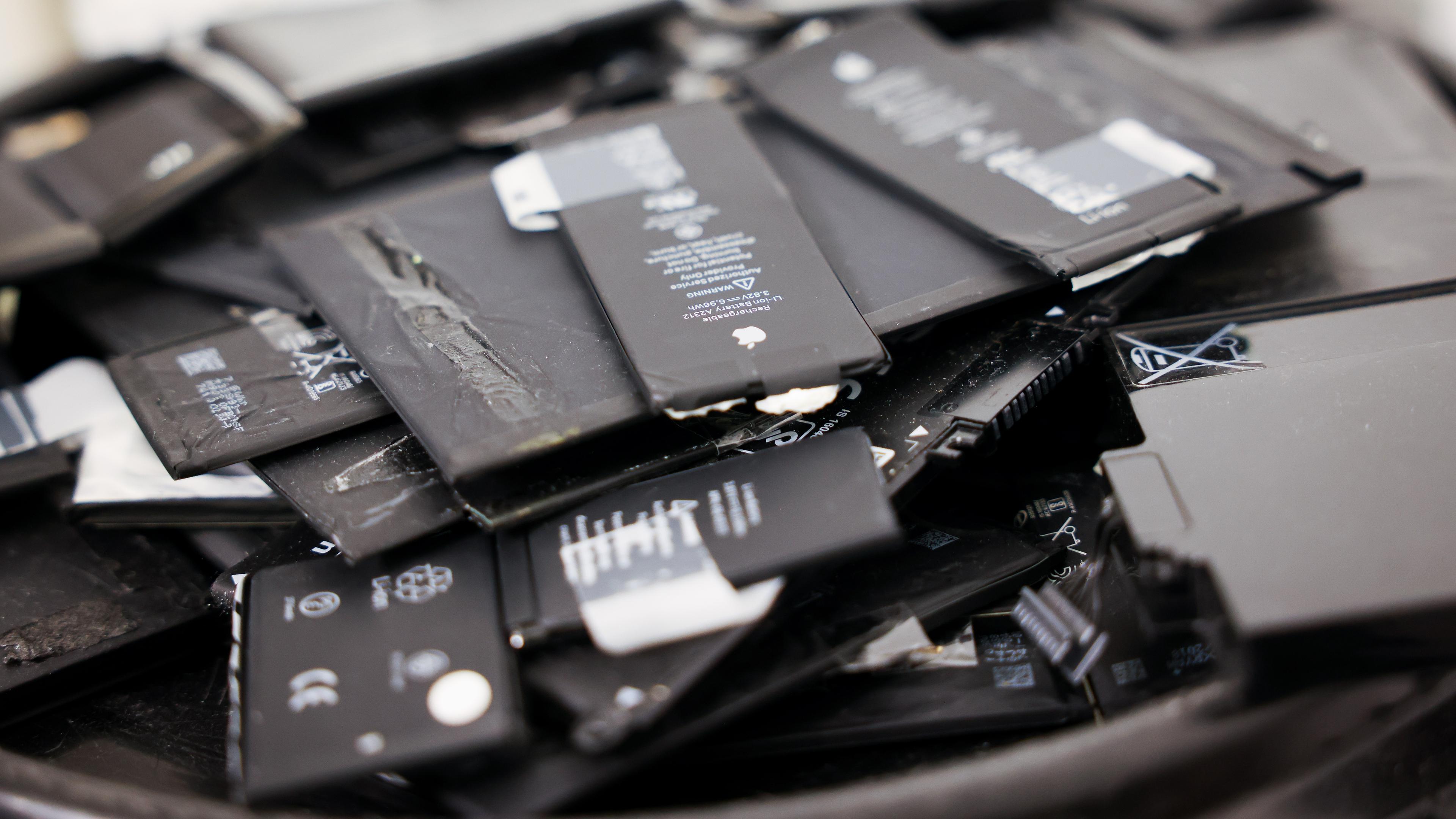 Alte Akkus von Smartphones und Tabletcomputern liegen auf einer Transporttonne für Hochenergiebatterien in einem kleinen Fachgeschäft für Handy-Reparaturen und Zubehör. In der EU sollen Kunden in Zukunft das Recht haben, bestimmte Geräte reparieren zu lassen.