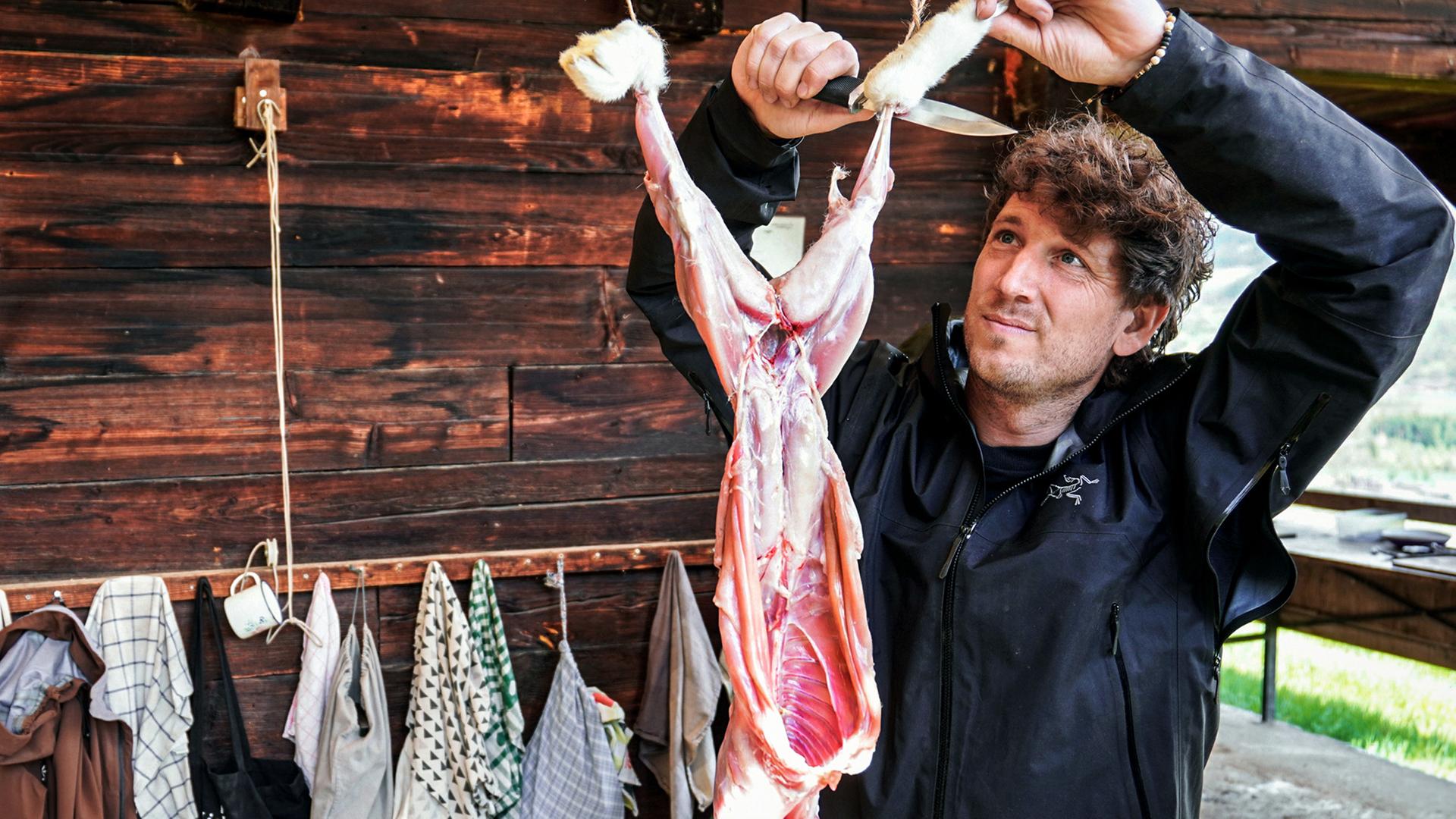 Donat Hofer häutet einen Hasen in der Naturschule Woniya.