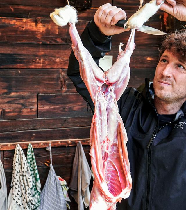 Donat Hofer häutet einen Hasen in der Naturschule Woniya.