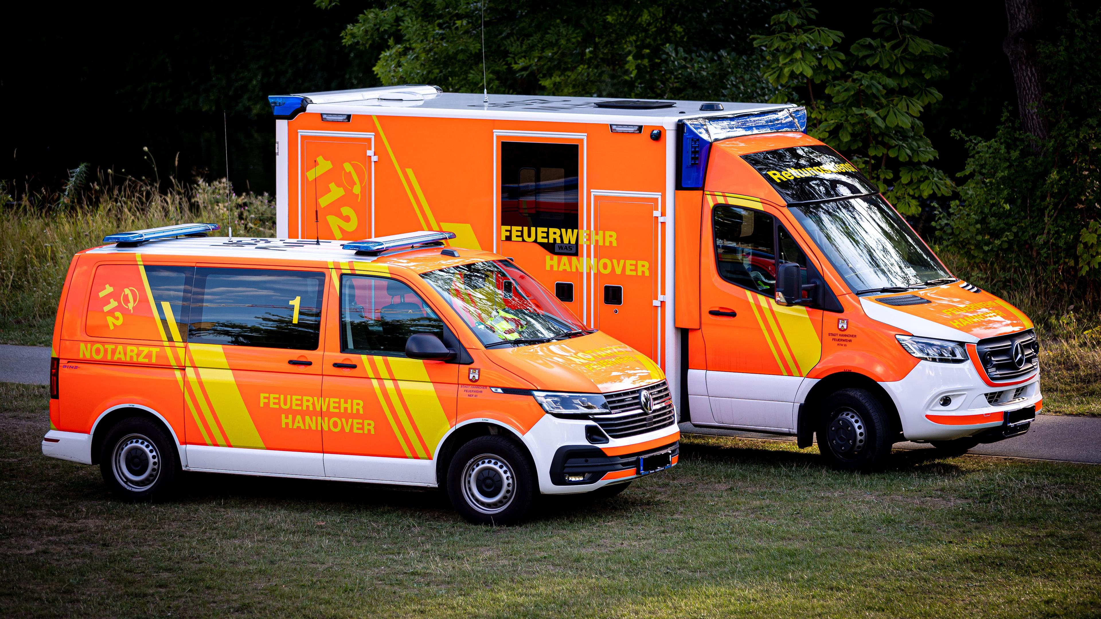 Niedersachsen, Hannover: Zwei Einsatzfahrzeuge vom Rettungsdienst stehen bei einem Einsatz auf einer Wiese an einem Weg. Archivbild