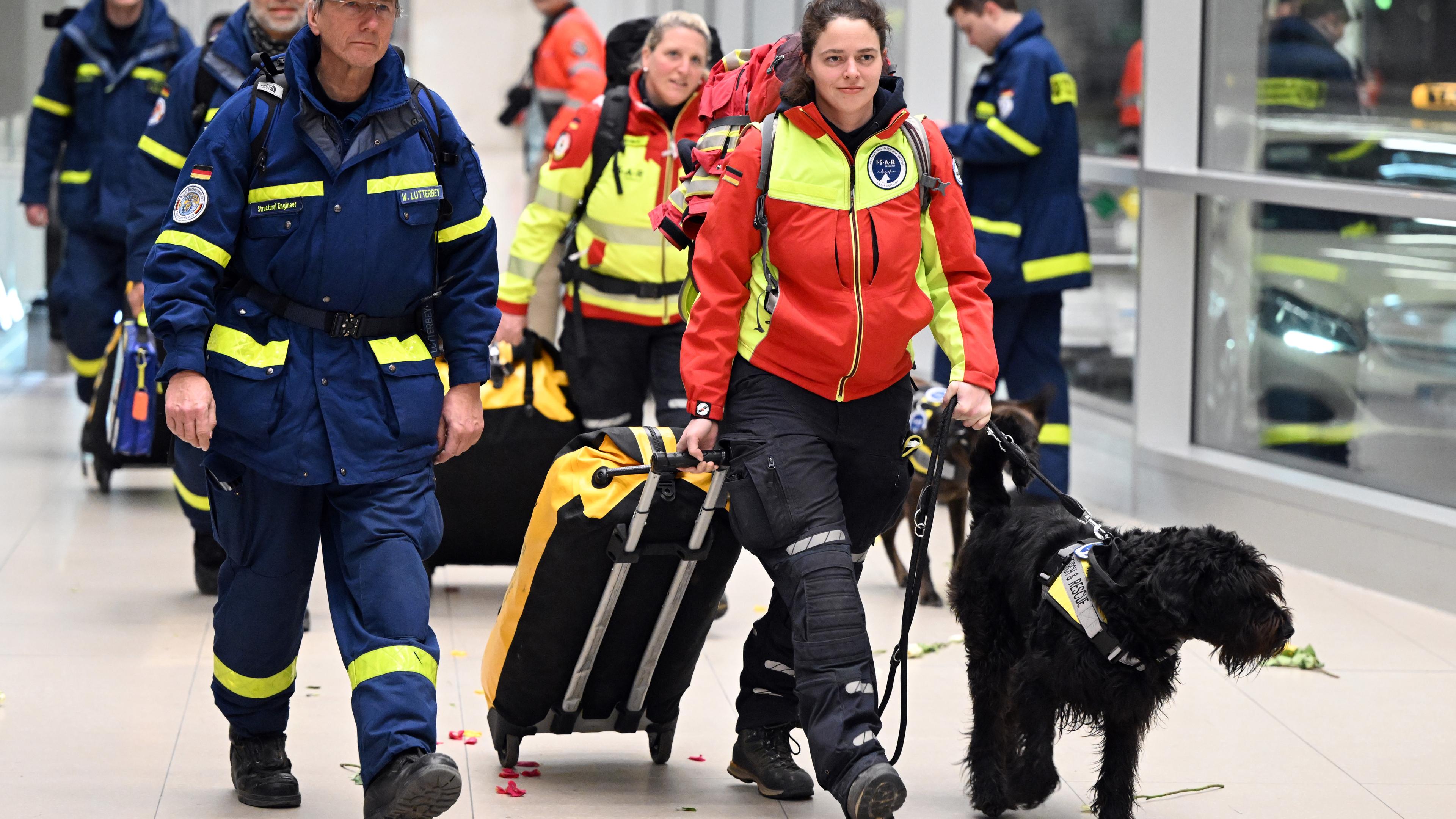 Rettungskräfte und ein Hund laufen einen Gang entlang.