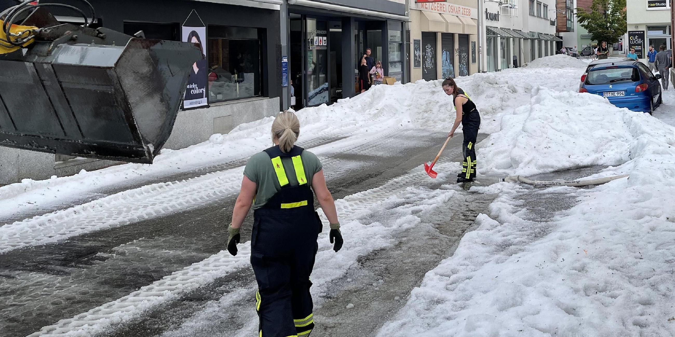 Reutlingen: Einsatzkräfte der Feuerwehr räumen Hagel von einer Straße. (Bild vom 04.08.2023)