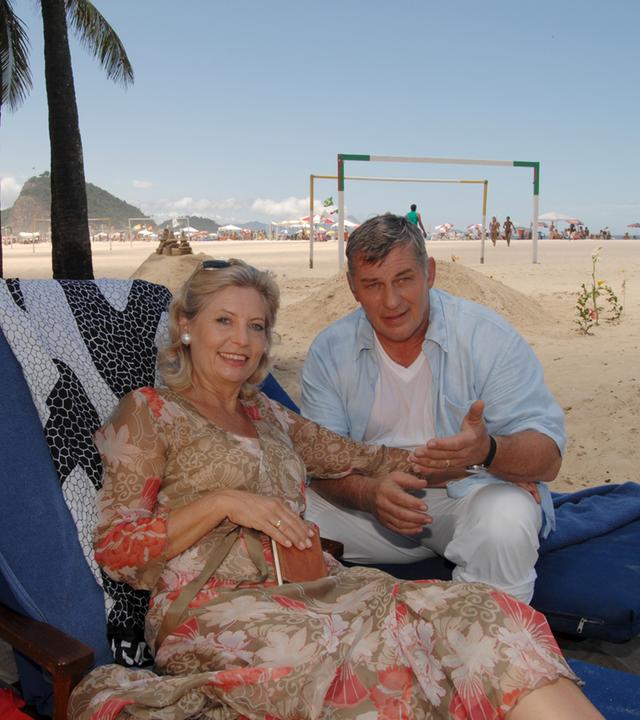 "Das Traumschiff: Rio de Janeiro": Auf Liegestühlen sitzen Brigitte (Sabine Postel) und Paul Eisfeld (Heinz Hönig) nebeneinander am Strand und lachen in die Kamera