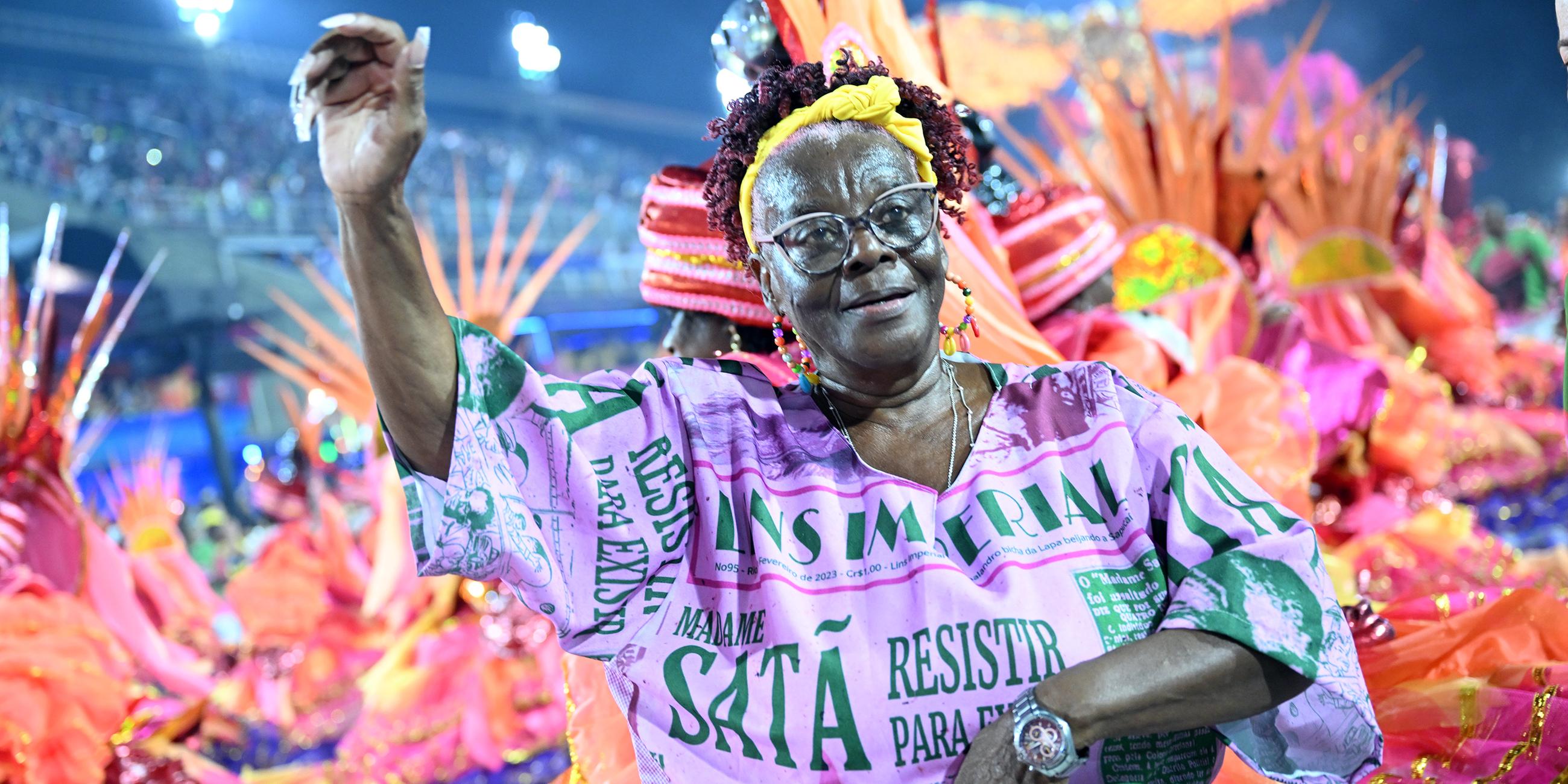 Ältere Frau feiert den Karneval vor dem Umzug im Hintergrund
