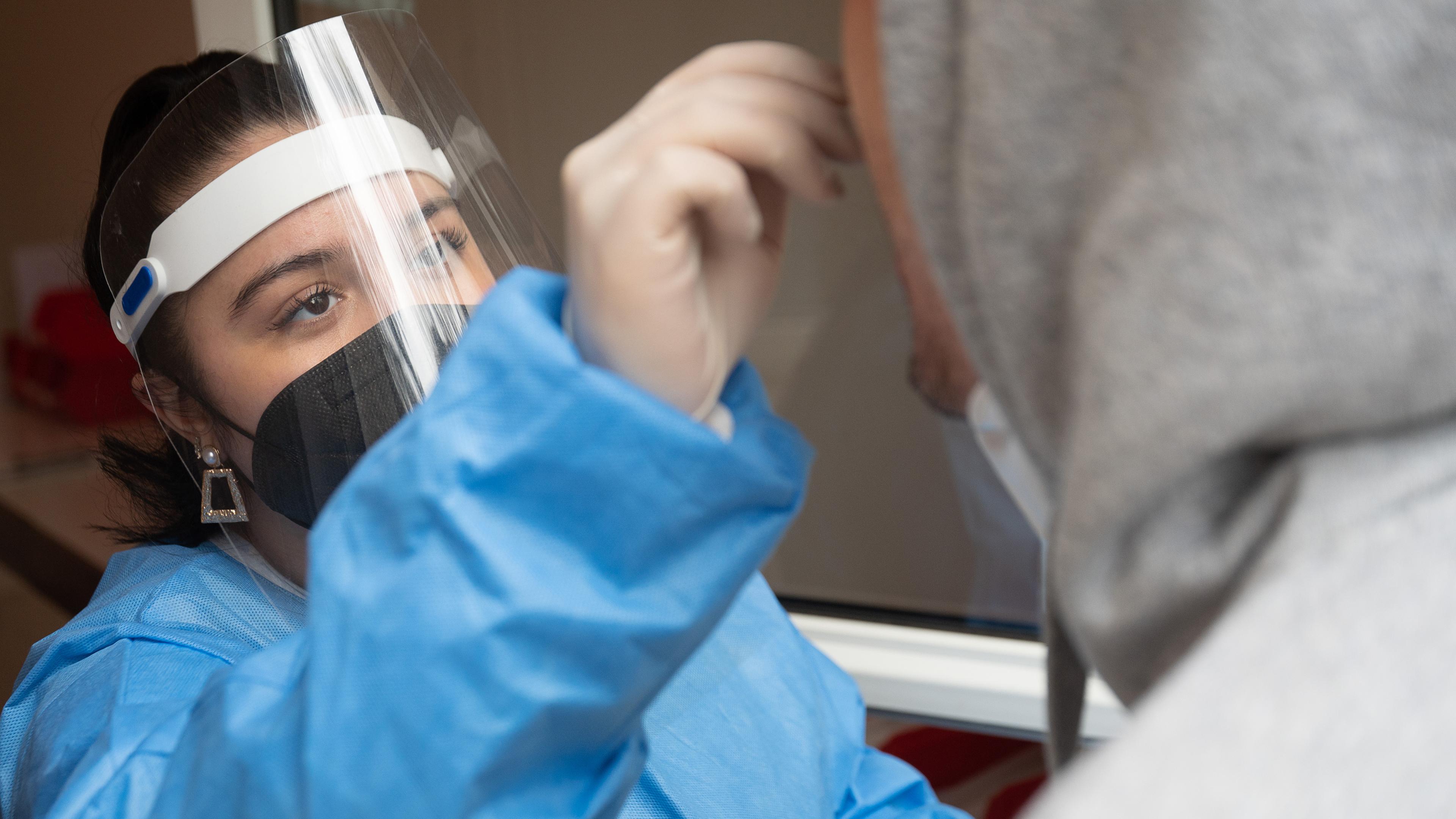 Eine Frau in Schutzkleidung führt einen Antigen-Schnelltest durch.