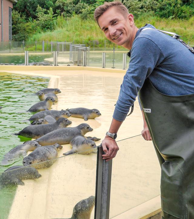 Eric lehnt an einer Glaswand, hinter der ein Robbenbecken zu sehen ist.