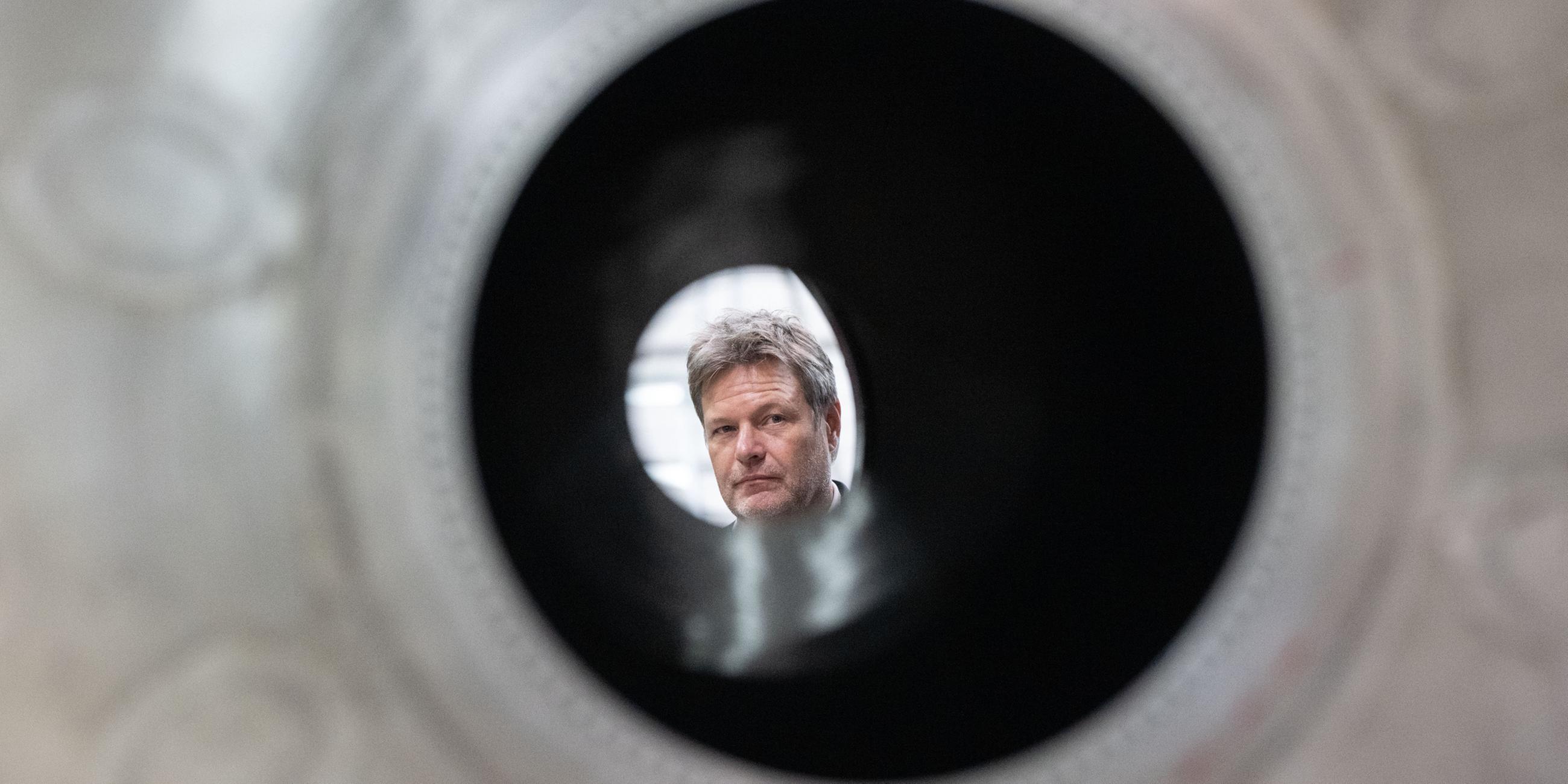Robert Habeck schaut während eines Rundgangs in einer Halle des Raumfahrtunternehmens Rocket Factory Augsburg durch einen Raketentank.