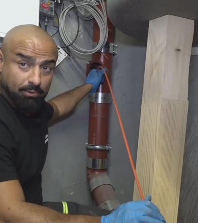 Auf dem Bild zu sehen ist ein männlicher Rohrreiniger bei seiner Arbeit.
