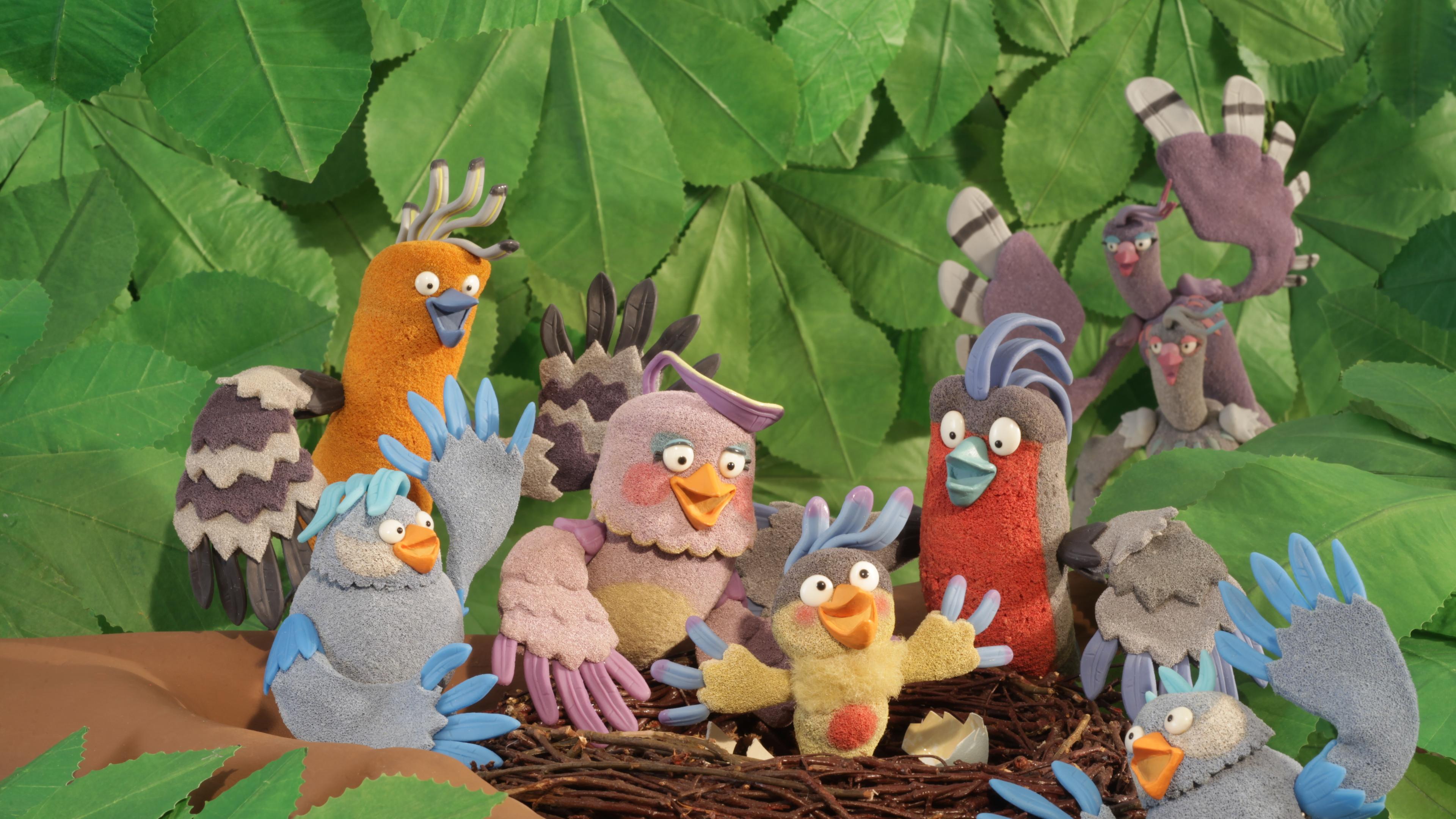 Eine Vogelschar umringt das Vogeljunge, das in der Mitte des Nests sitzt.