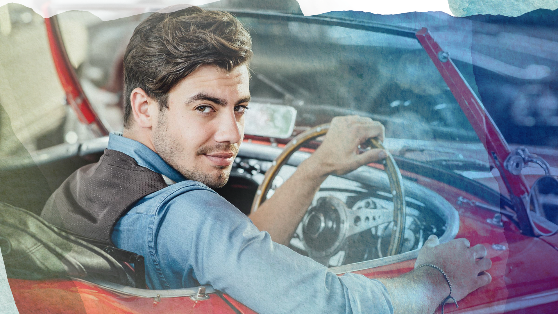 Bruno (Florian Wünsche) sitzt in seinem rot-weißen Oldtimer-Cabrio am Steuer und blickt lächelnd über die Schulter.