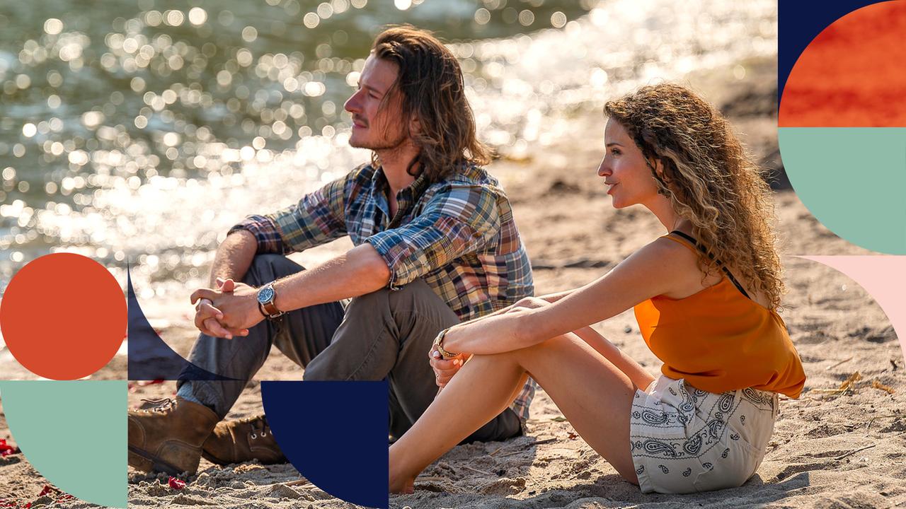 "Inga Lindström: Rosenblüten im Sand": Bei frühabendlicher Stimmung sitzen Catrine (Nadine Menz) und Pelle (Stefan Gorski) in die Ferne träumend am glitzernden Wasser im Sand.