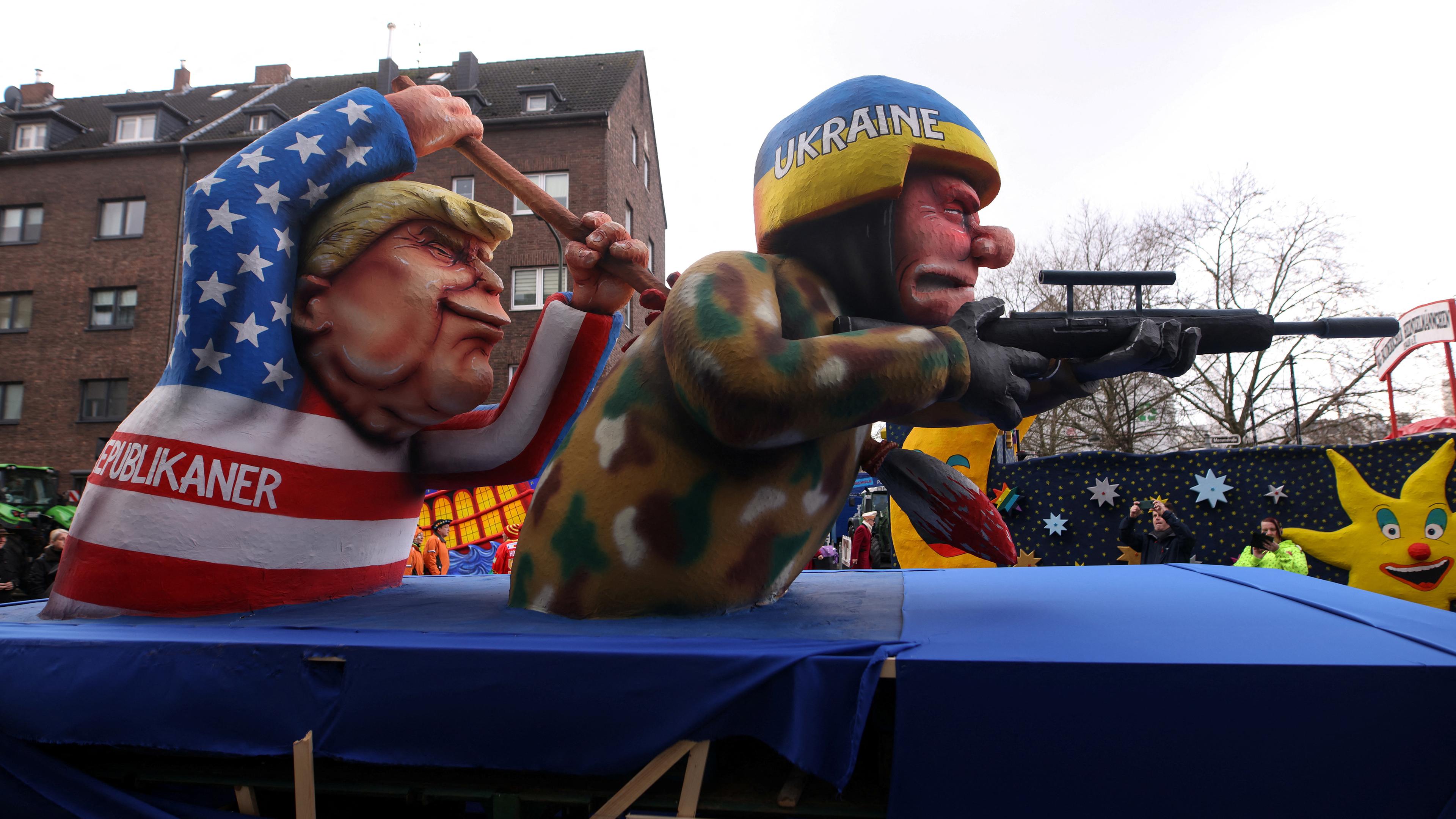 Ein Karnevalswagen, der den ehemaligen US-Präsidenten und republikanischen Präsidentschaftskandidaten Donald Trump und einen ukrainischen Soldaten zeigt, ist am Tag der traditionellen Rosenmontag-Karnevalsparade in Düsseldorf, Deutschland, am 12. Februar 2024, abgebildet. 