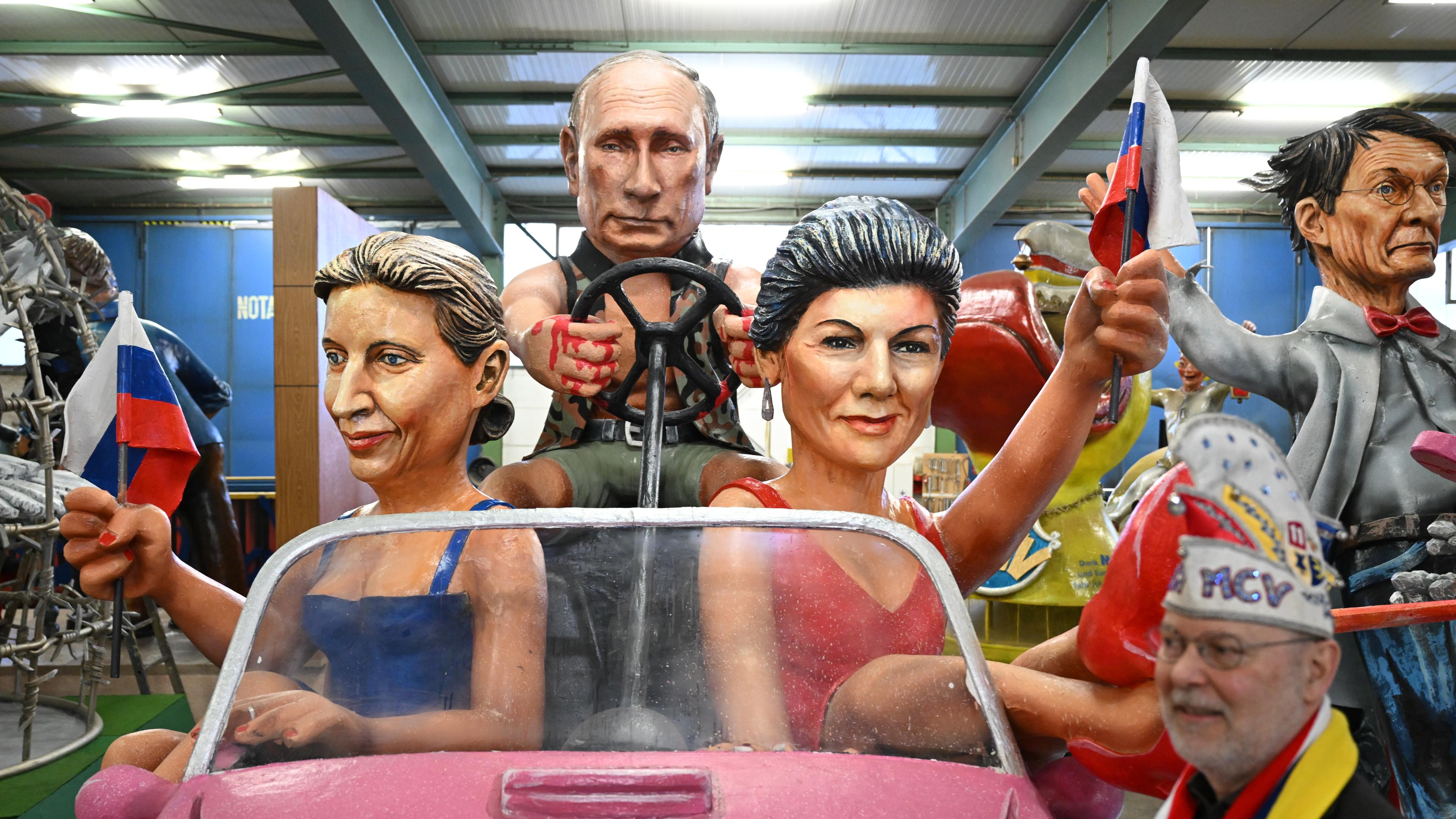 Der russische Präsident Wladimir Putin (M), Alice Weidel (AfD, l) und Sahra Wagenknecht (BSW) werden als Barbies und Ken bei der Vorstellung der Motivwagen für den Mainzer Rosenmontagszug in der Wagenhalle des Mainzer Carneval-Vereins (MCV) präsentiert. 