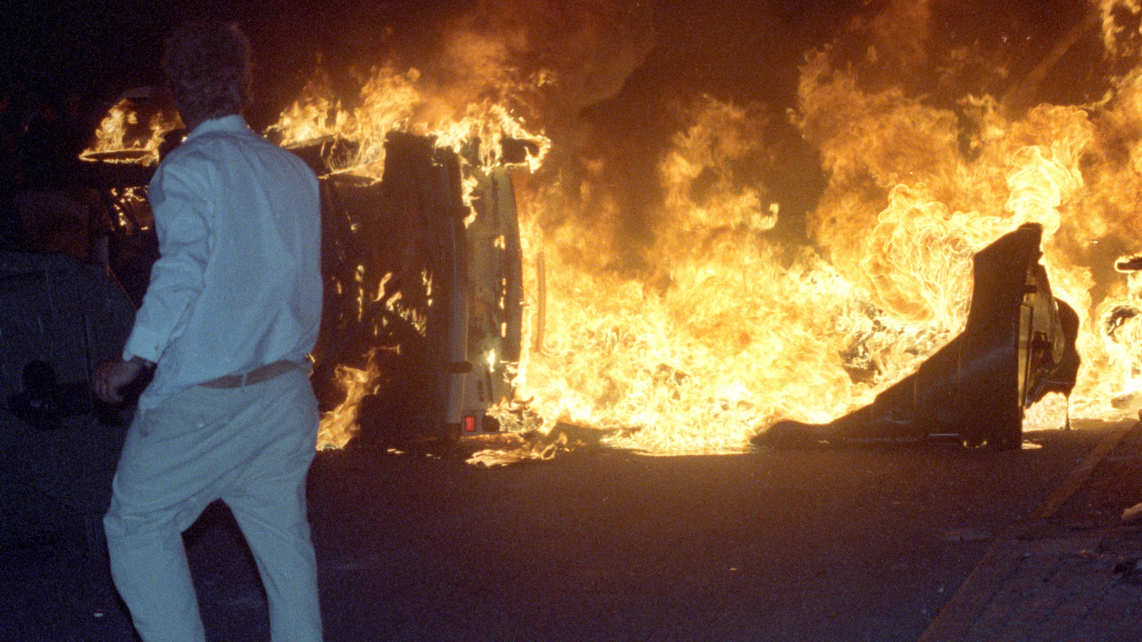 Ein Randalierer steht vor einem brennenden Trabi in Rostock-Lichtenhagen
