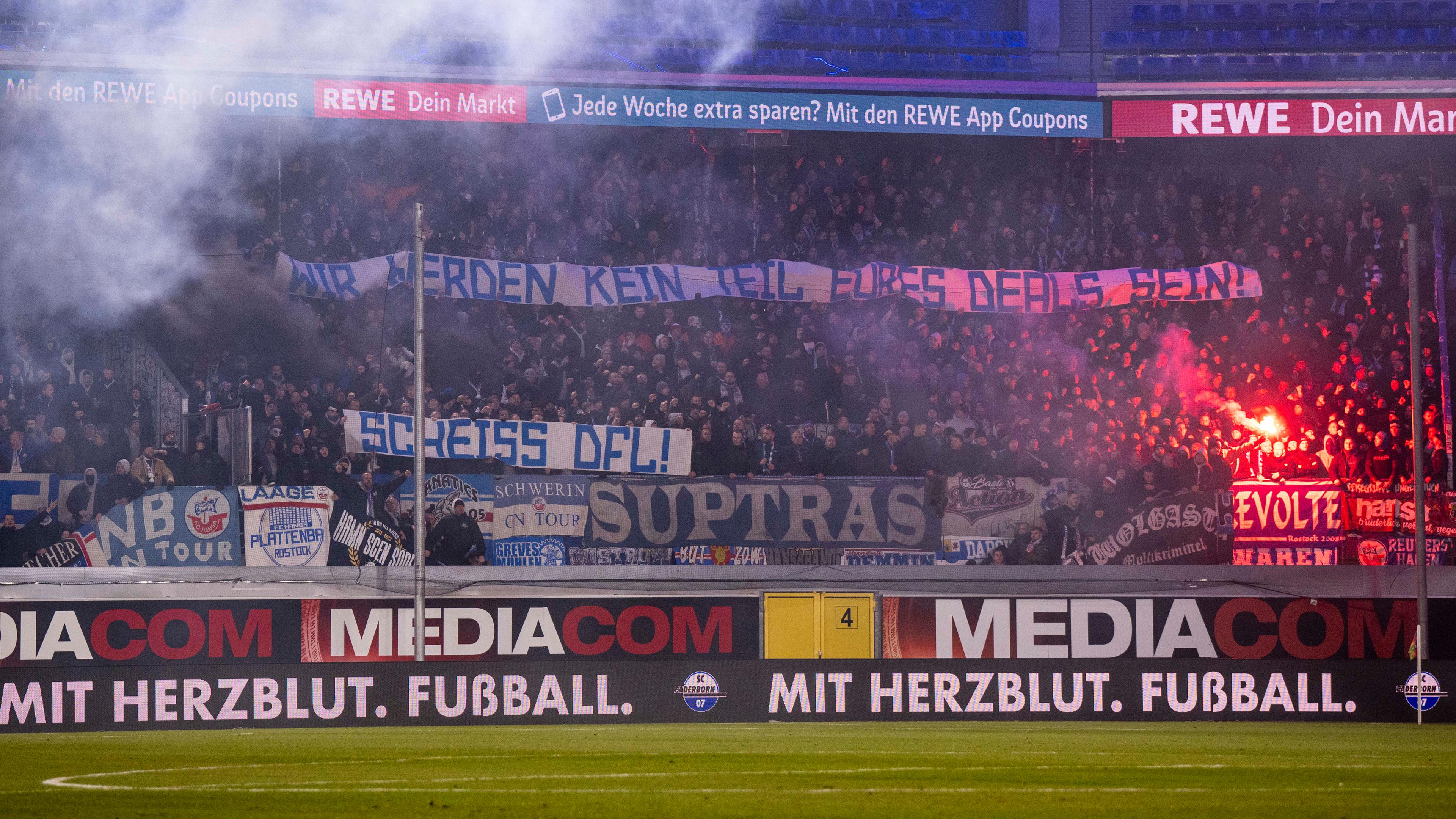 Rostocker Fans protestieren mit Bannern und Pyrotechnik gegen die DFL und Investoren am 15.12.2023.