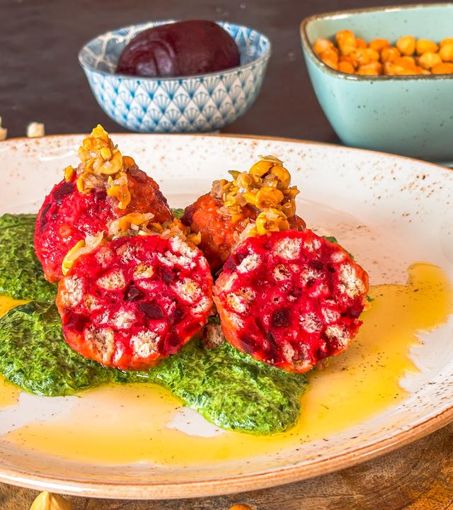 Rote-Bete-Knödel mit Rahmspinat auf einem Teller serviert.