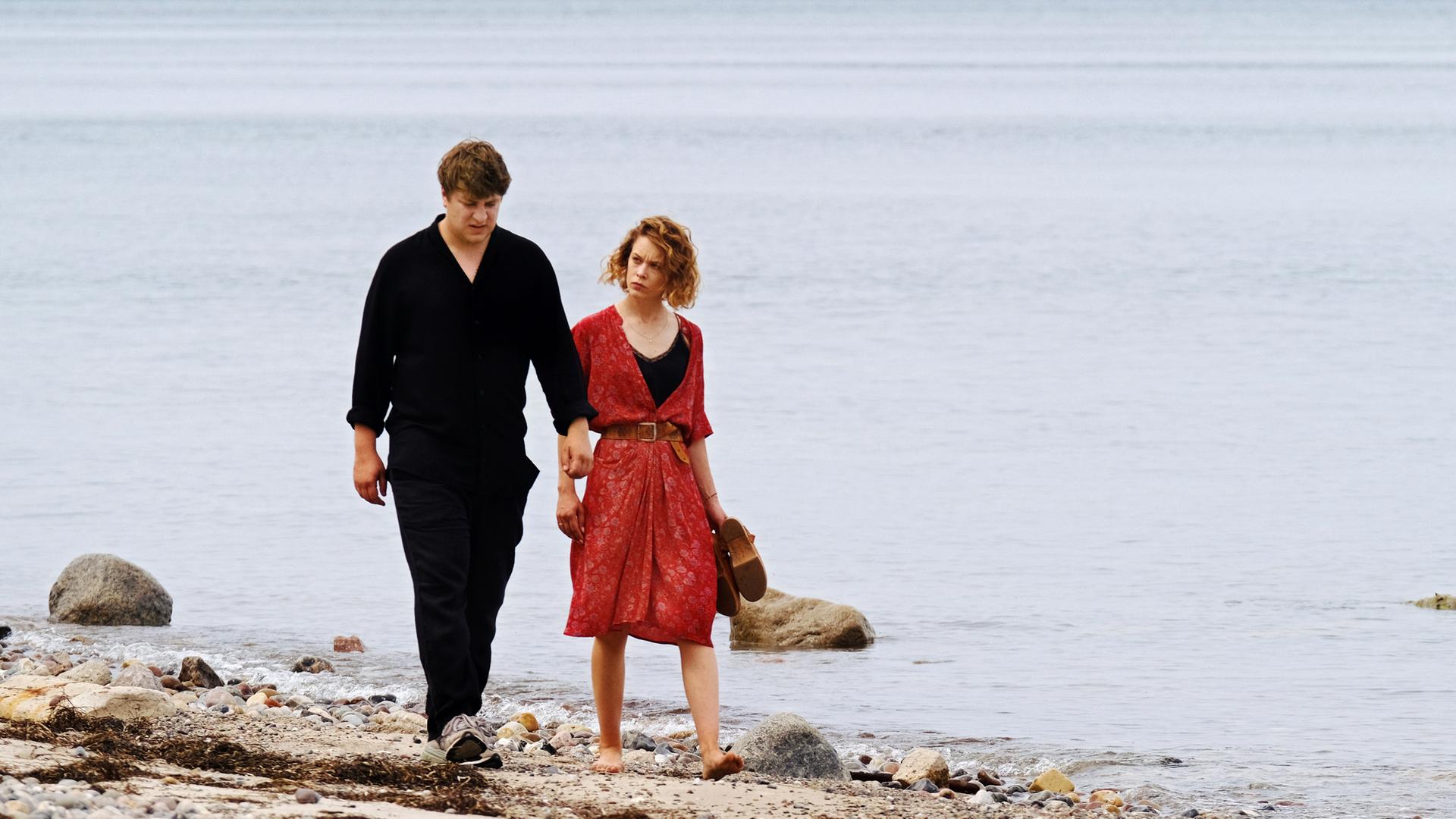 Leon (Thomas Schubert) und Nadja (Paula Beer) laufen nebeneinander am Strand entlang.