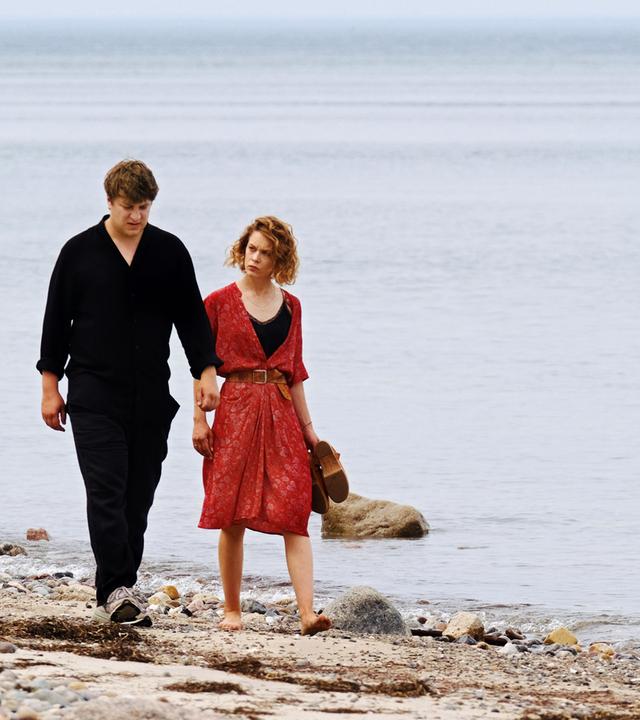 Leon (Thomas Schubert) und Nadja (Paula Beer) laufen nebeneinander am Strand entlang.