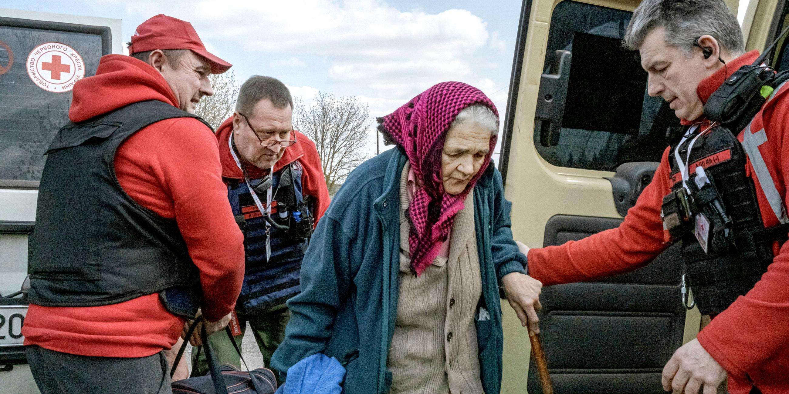 Einer Ukrainerin wird während eines, vom ukrainischen Roten Kreuz organisierten, Evakuierungsprozesses beim Einsteigen in ein Fahrzeug geholfen.