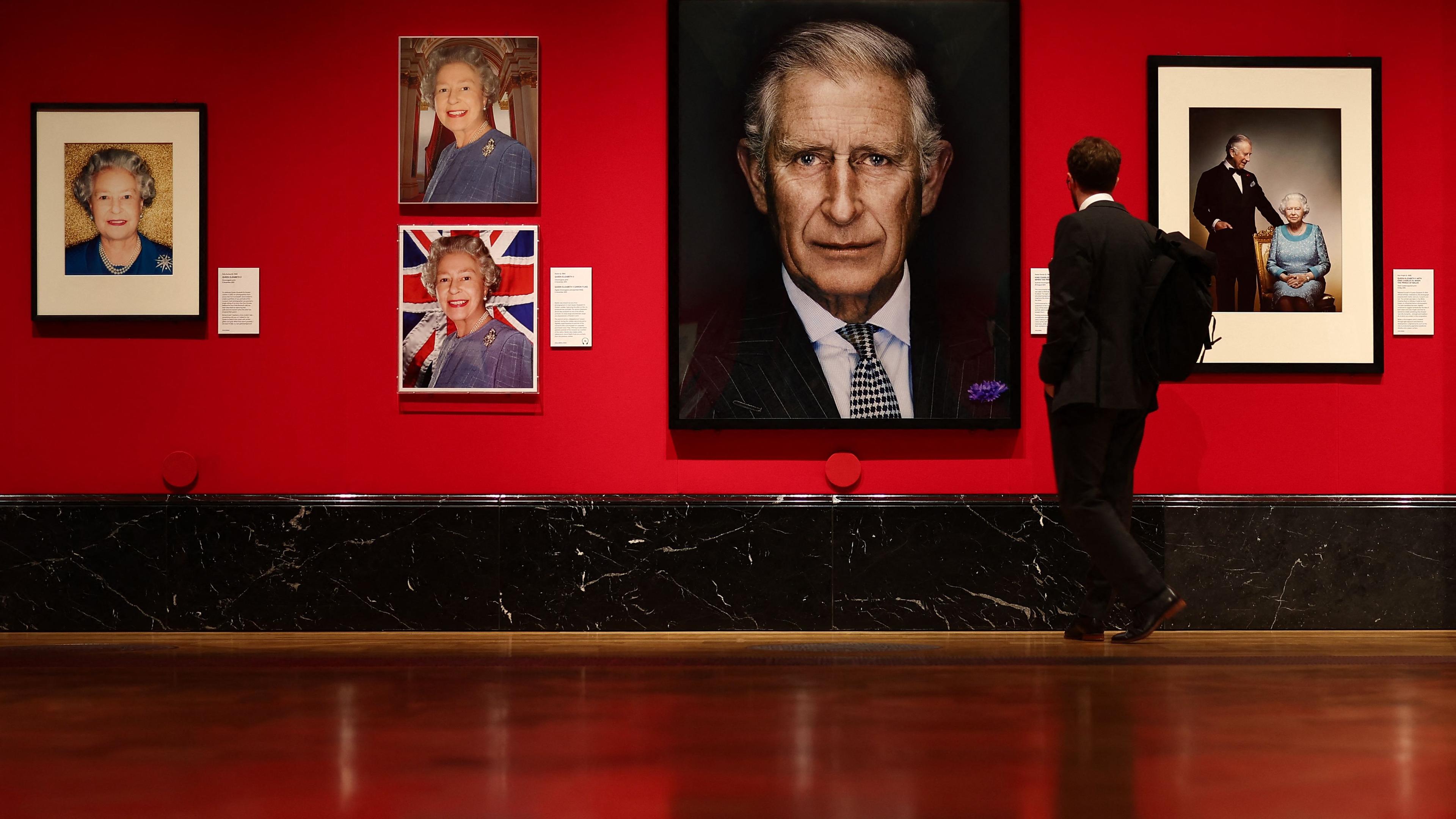 In einer Galarie hängen Porträtfotografien der Queen und King Charles.