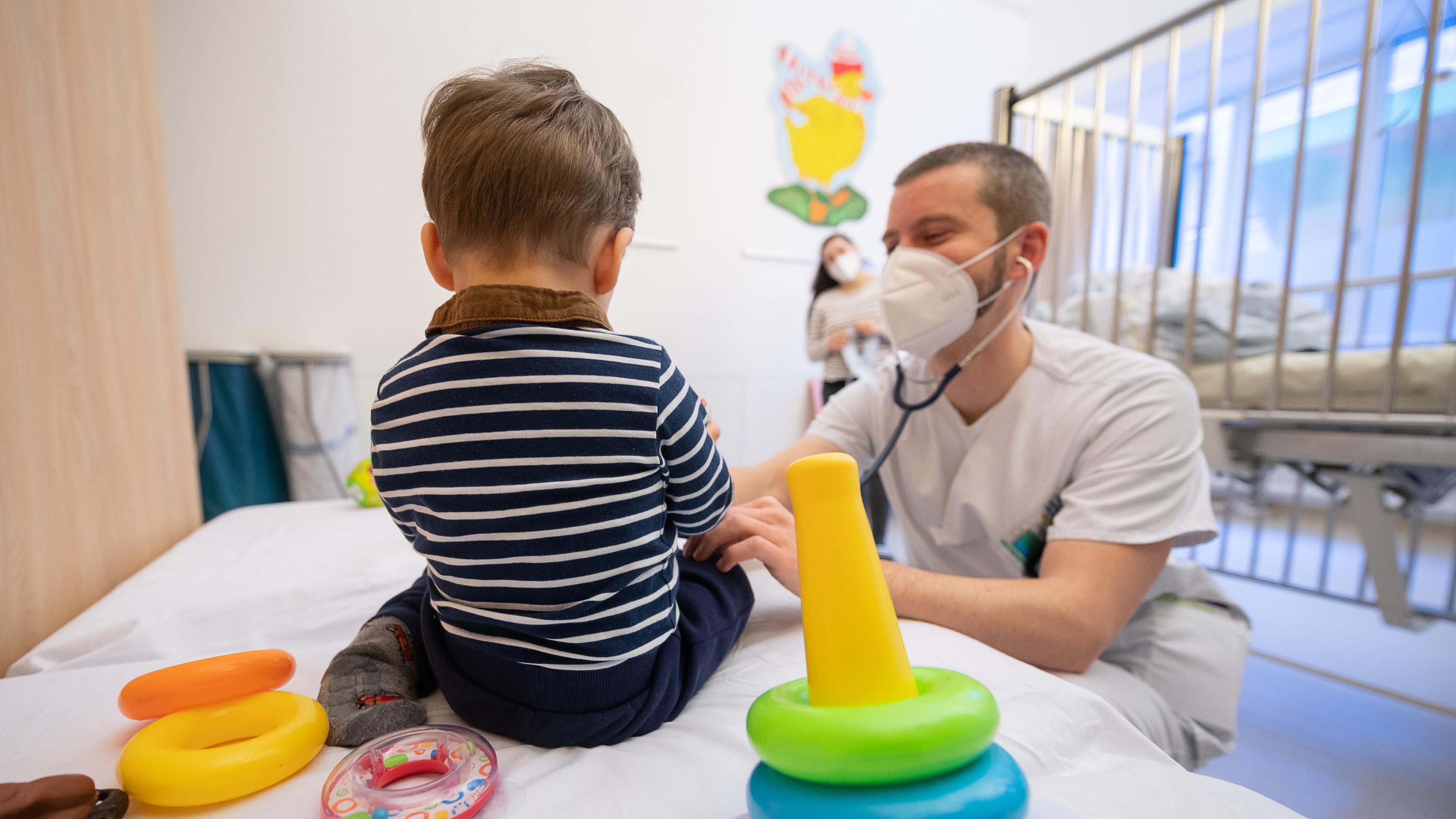 Ein Arzt untersucht in einer Kinderklinik ein Kind.