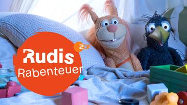 Rabe Rudi vor seinem bunt zusammengezimmerten, schiefen Holzhaus