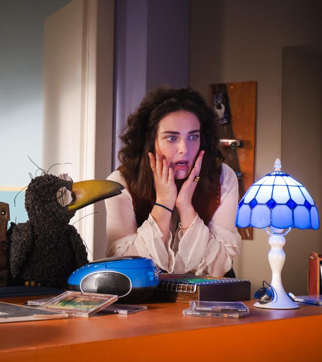 Koffer, Rudi und Siebenstein schauen staunend auf eine Lampe, die blau leuchtet.