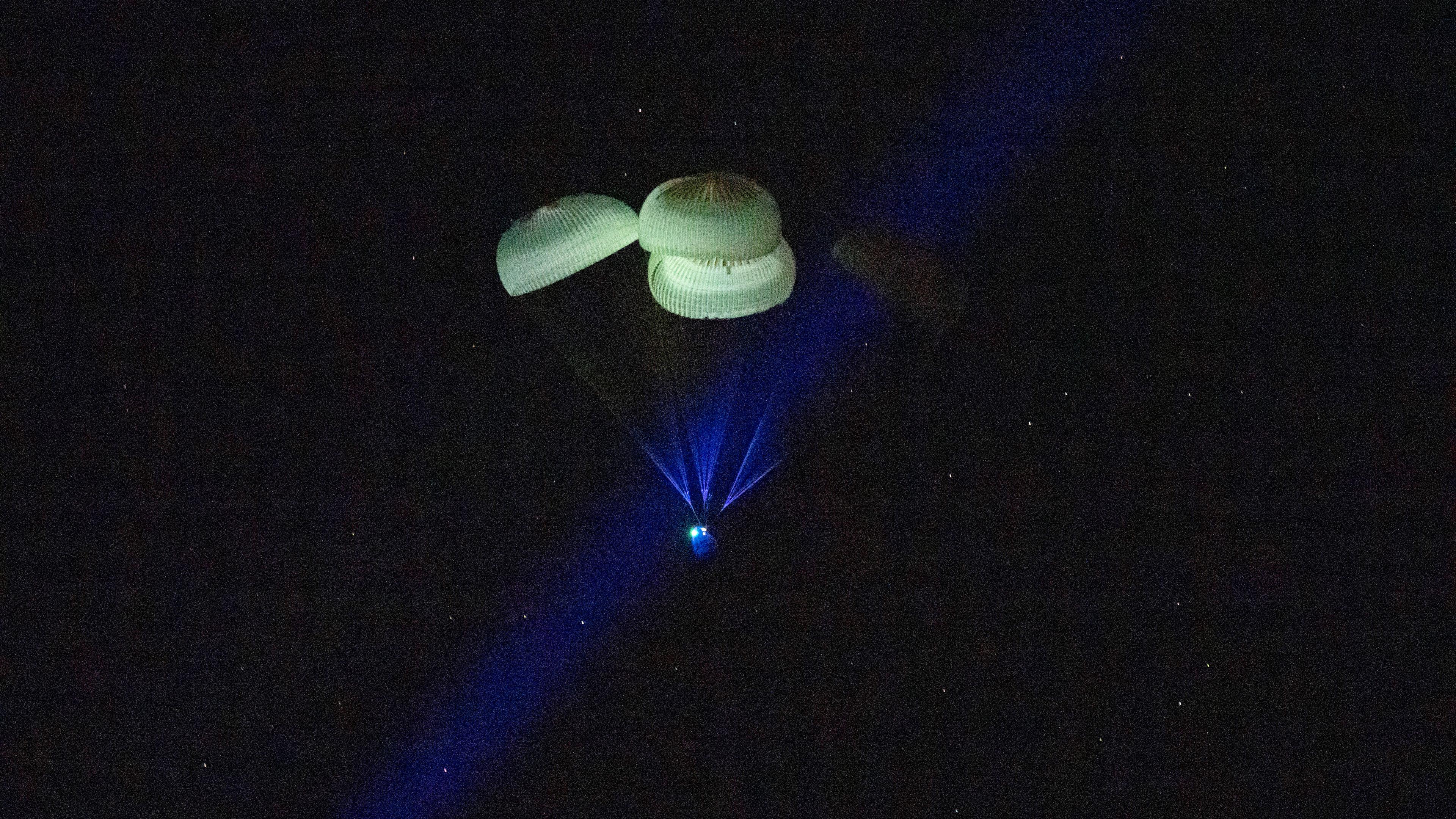Eine SpaceX-Kapsel, gebremst durch Fallschirme, landet auf der Wasseroberfläche des Golfs von Mexiko.