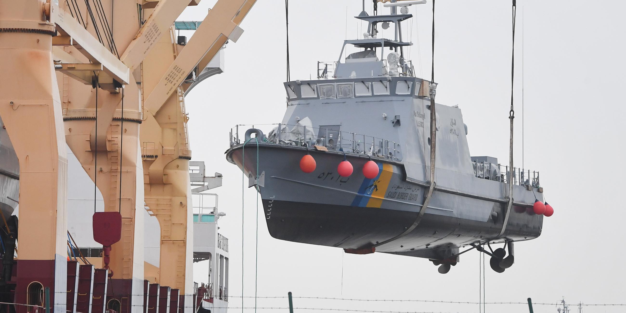 Mecklenburg-Vorpommern, Mukran: Ein Küstenschutzboot wird  im Hafen auf ein Transportschiff verladen. Archivbild