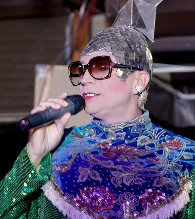 Eine Person steht mit einem Mikrofon auf der Bühne und singt.