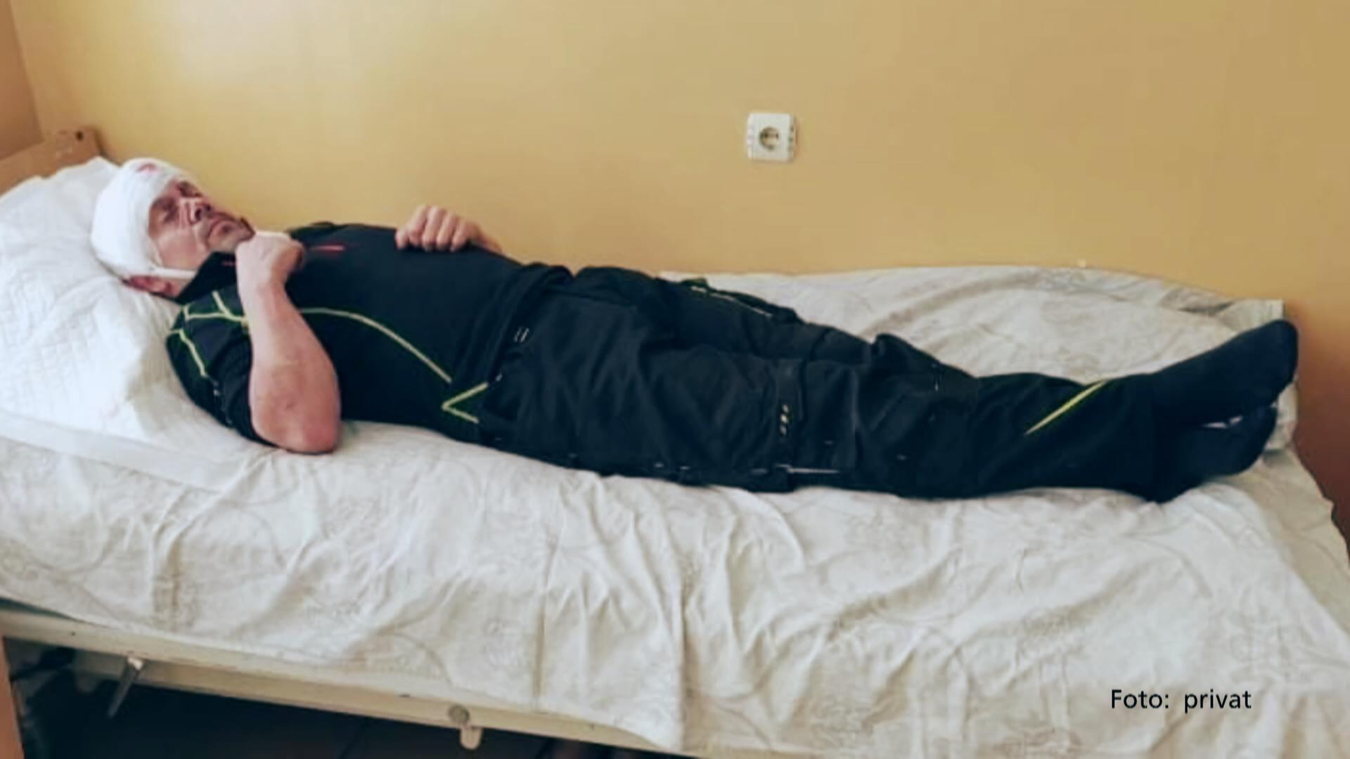 Verletzter liegt mit Kopfverband auf einem Krankenhausbett 