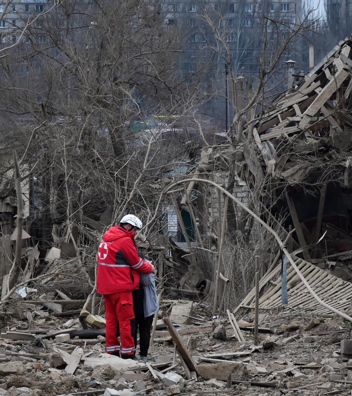 Ein medizinischer Helfer umarmt eine Frau vor einem zerstörten Haus bei Saporischschja in der Ukraine.