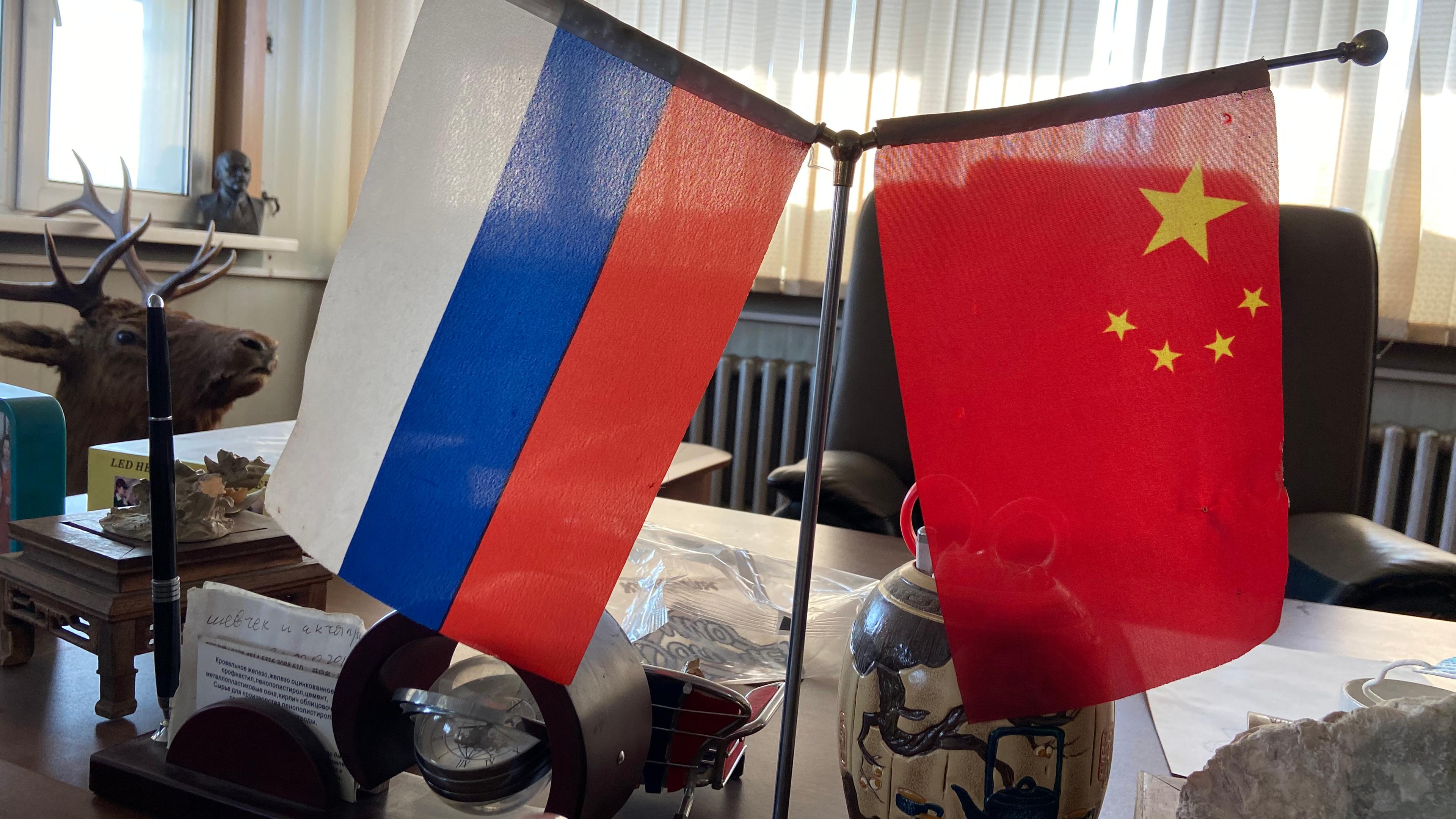 Die Fahnen von Russland und China stehen auf einem Schreibtisch in Blagoweschtschensk