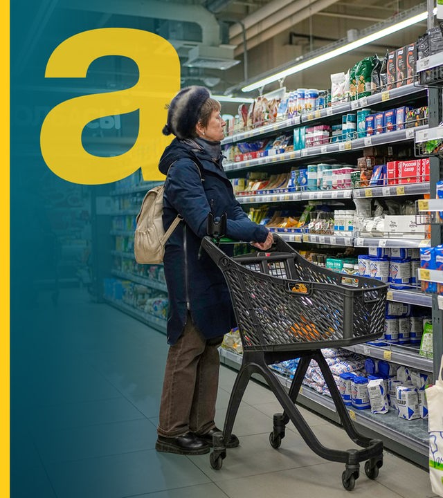 Eine Frau mit einem Einkaufswagen vor einem regal im Supermarkt