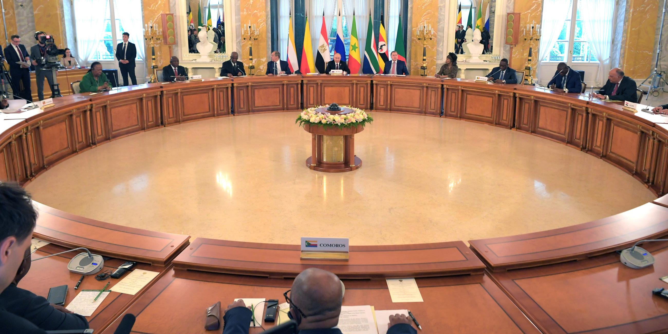 Wladimir Putin und eine Delegation afrikanischer Staats- und Regierungschefs sitzen am kreisförmig angeordneten Tischen.