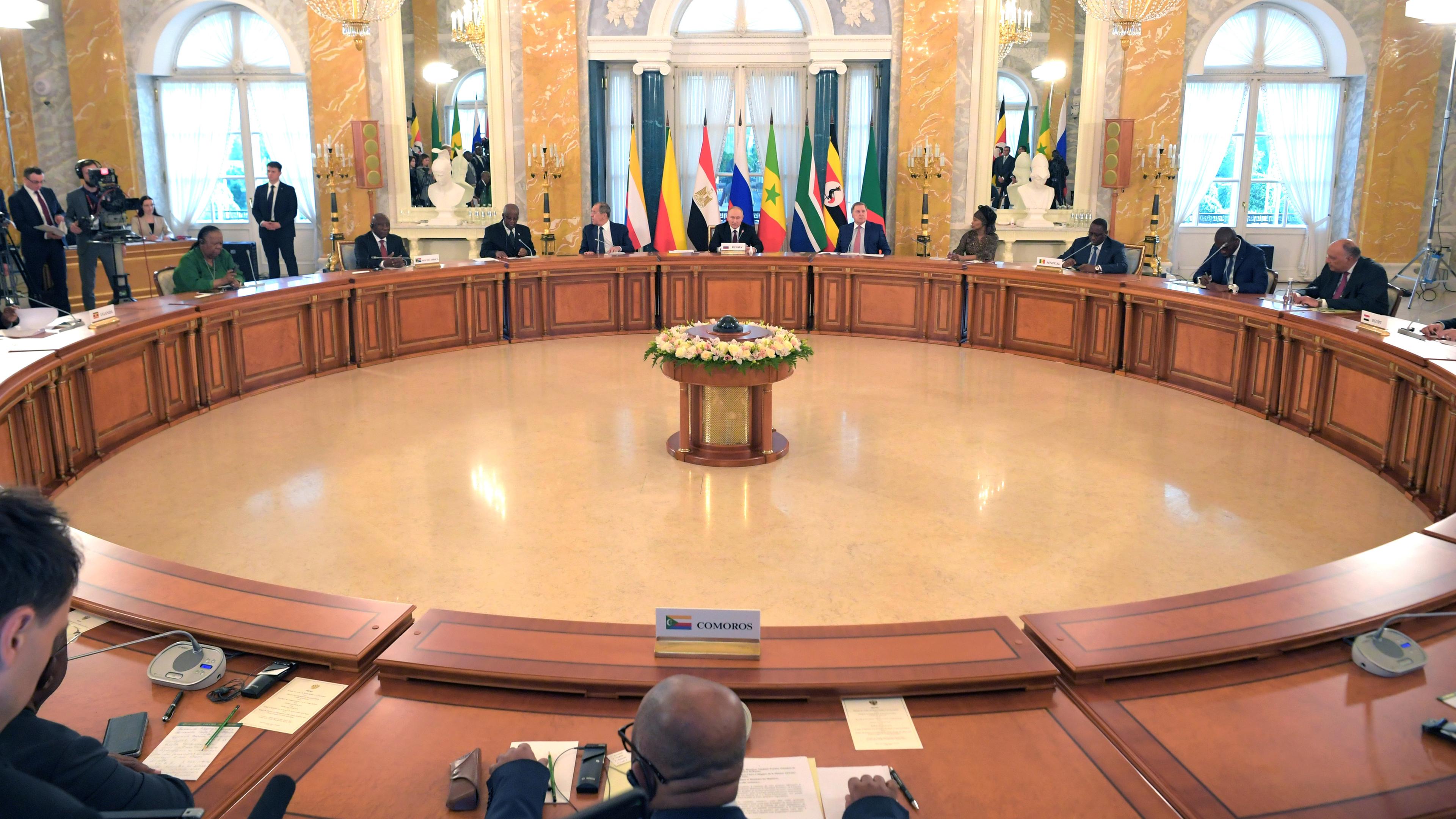 Wladimir Putin und eine Delegation afrikanischer Staats- und Regierungschefs sitzen am kreisförmig angeordneten Tischen.