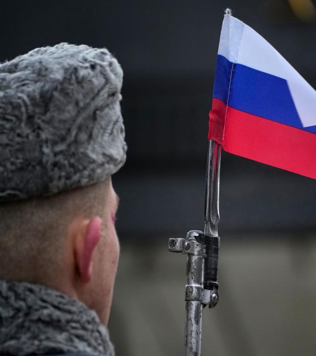 Ein Soldat der Ehrengarde hält ein Gewehr mit einer russischen Fahne auf dem Bajonett.