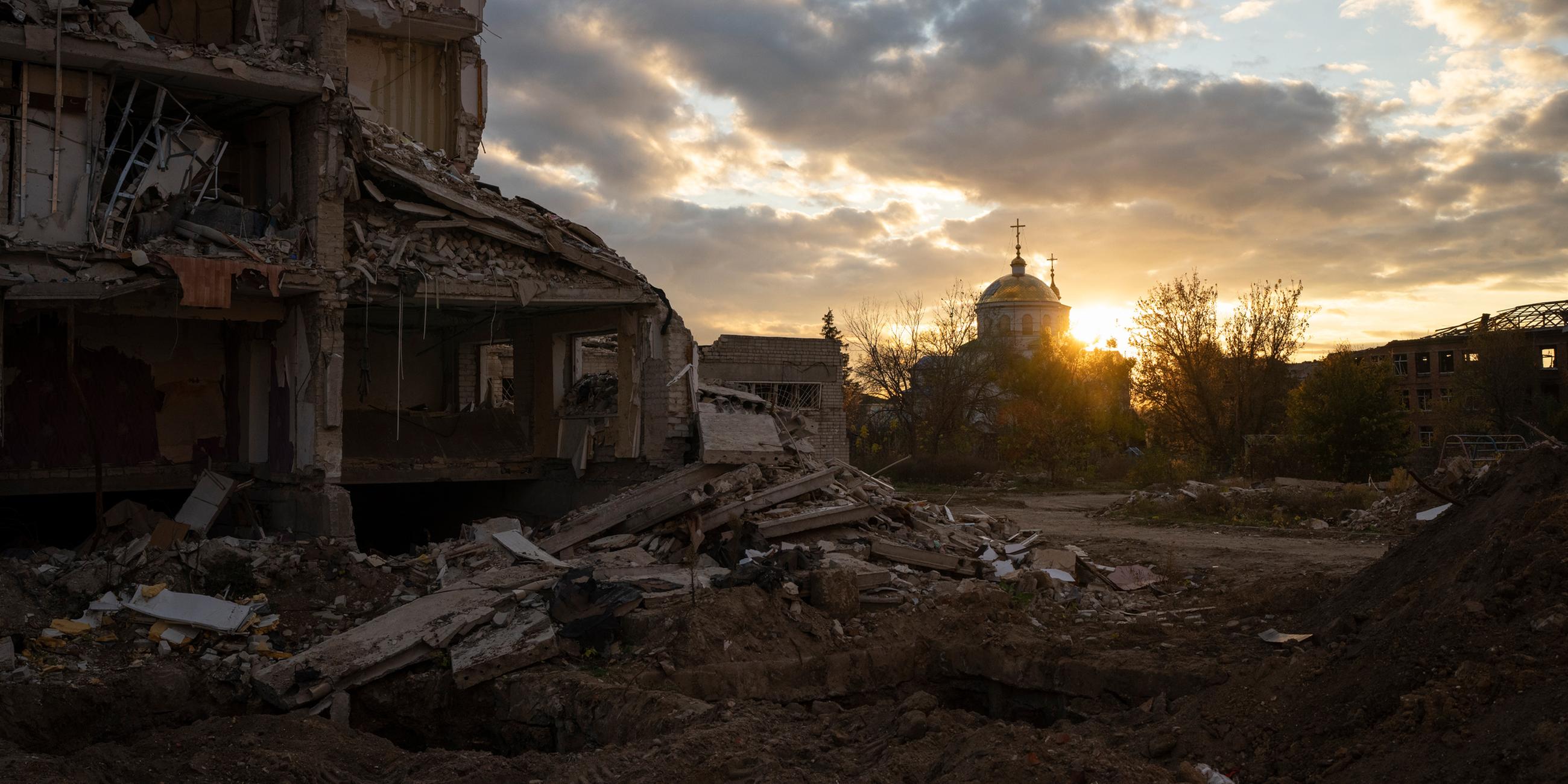 Die Sonne geht über einem zerstörten Gebäude in Izyum, Ukraine, unter, am 24.10.2023.