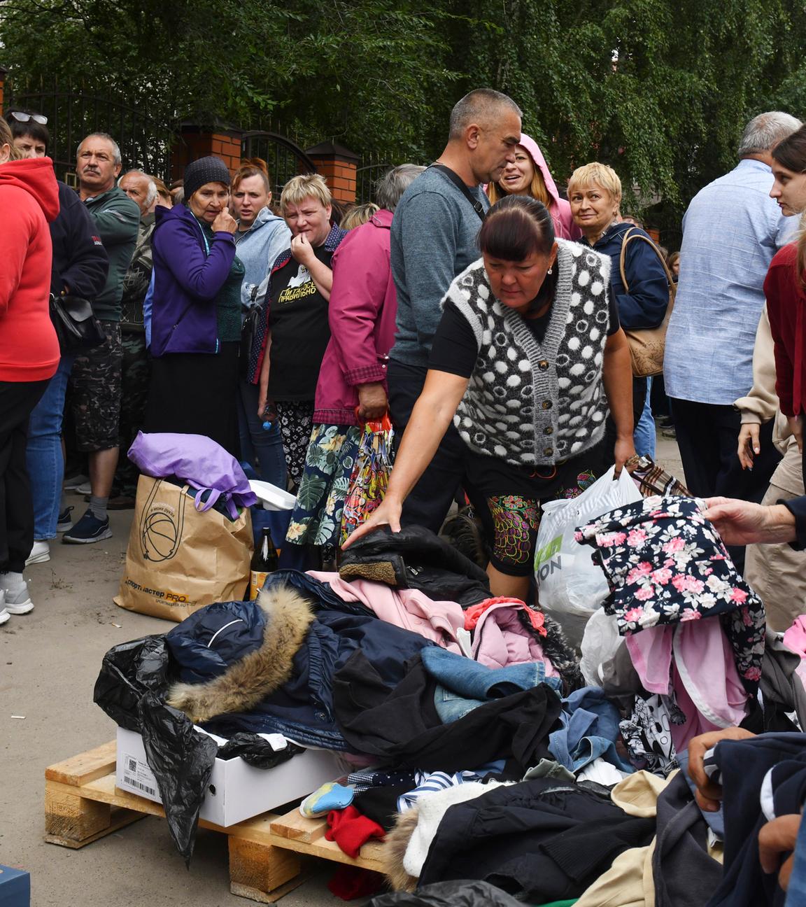 12.08.2024, Russland, Kursk: Menschen, die vor den Kämpfen zwischen russischen und ukrainischen Streitkräften evakuiert wurden, warten in einem Verteilungszentrum auf humanitäre Hilfe.