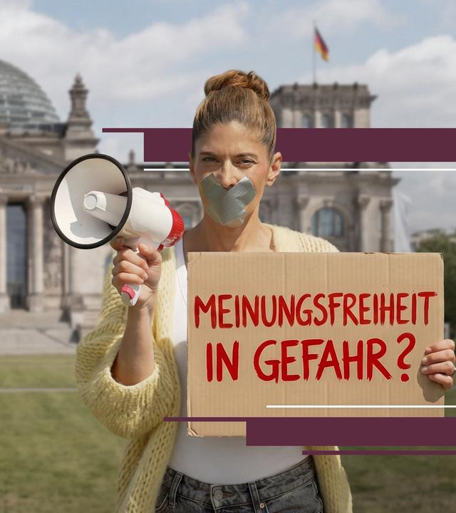 Moderatorin Katty Salié steht vor dem Reichstagsgebäude in Berlin. Sie hält ein Megafon in der rechten Hand und ein Pappschild mit der Aufschrift „Meinungsfreiheit in Gefahr?“ in der linken. Ihr Mund ist mit silbernem Klebeband überklebt.